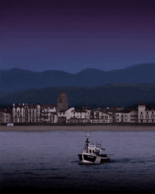 a boat in the water with a city in the background and mountains in the background