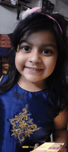 a little girl wearing a blue dress and a pink headband