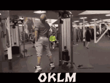 a man is standing in a gym next to a machine that says oklm .