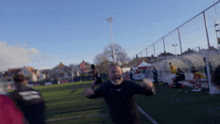 a blurry picture of a soccer field with a man wearing a black shirt with the word adidas on it