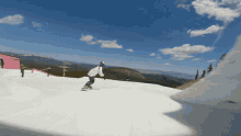 a snowboarder rides down a snow covered slope with a pink building in the background that says ' altitude '