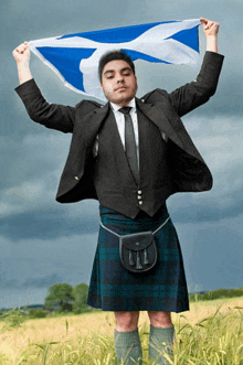 a man in a kilt is holding a scottish flag over his head