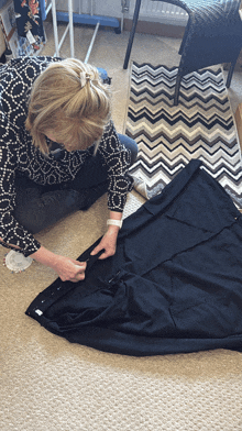 a woman is kneeling down on the floor with a piece of black fabric in front of her