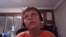 a young boy wearing headphones is looking up at something