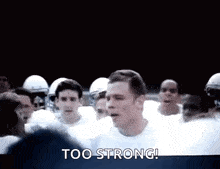 a group of football players are standing in a huddle with the words `` too strong '' written on the screen .