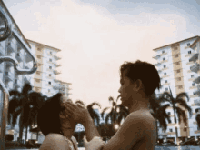 a man and a woman are touching each other 's faces by a pool