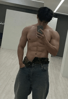 a shirtless man taking a picture of himself in a mirror