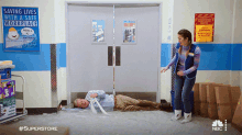 a woman stands next to a man laying on the floor in front of a sign that says saving lives with a safe workplace