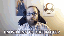 a man with a beard wearing glasses and headphones says i 'm willing to dive in deep