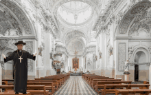 a priest stands in the middle of a church with rows of wooden benches