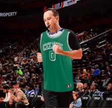 a man is standing on a basketball court wearing a green celtics jersey .