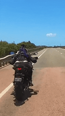 a person riding a motorcycle on a highway with a license plate that says 4577zn