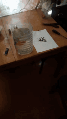 a plastic bottle of water sits on a wooden table next to a piece of paper