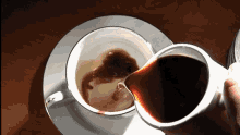 a cup of coffee is being poured into another cup on a saucer