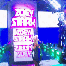 a woman is standing in front of a sign that says zoey stark on it