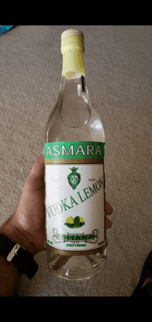 a bottle of asmara vodka lemon is being held in someone 's hand