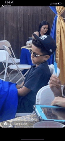 a young boy wearing a new york yankees hat sits in a chair