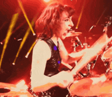 a woman with red hair is playing drums on a stage with lights behind her