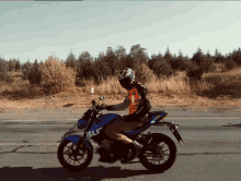 a person is riding a blue suzuki motorcycle on the road