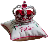 a red crown sits on a white pillow with pablo embroidered on it