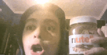 a child is holding a jar of nutella in front of his face