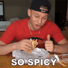 a man in a red shirt is eating a taco and giving a thumbs up with the word so spicy behind him