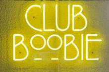 a neon sign that says club boobie is hanging on a wall