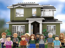 a lego family poses in front of a house