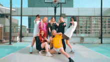 a group of young women are posing for a picture on a basketball court with a basketball hoop in the background .