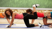 a group of women are doing exercises on yoga mats with a resistance band .