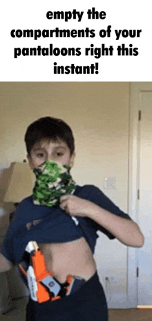 a boy wearing a bandana and a nerf gun on his stomach is standing in a living room .