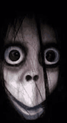 a close up of a scary face with big eyes and a smile in the dark .