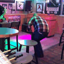 a man in a plaid shirt sits on a stool in a bar with a poster on the wall that says western