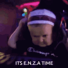 a baby wearing headphones and a headband says " its e.n.z.a. time "