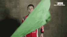 a man in a red and white racing suit holds a green cloth