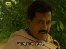 a man with a mustache is standing in front of a tree with a foreign language on his face .