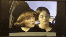 two women are looking out of a car window and one has glasses on