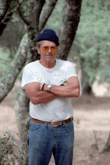 a man with his arms crossed is wearing sunglasses and a white shirt