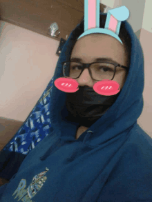 a person wearing a mask and bunny ears has a blue hoodie on