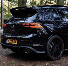 a black volkswagen gti is parked in a forest