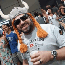 a man wearing a viking hat and sunglasses is standing in front of a crowd .