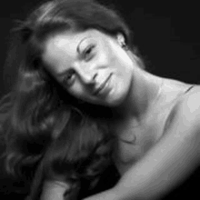 a black and white photo of a woman with long hair and a smile on her face .