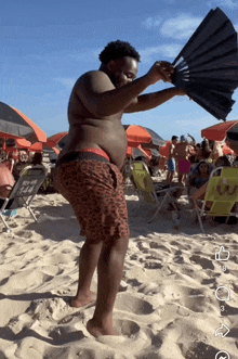 a man holding a fan on a beach with a chair that says new york