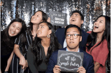 a group of people pose in a photo booth with one man holding a sign that says " all the single ladies "