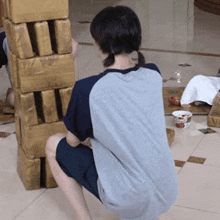 a person squatting down in front of a stack of cardboard blocks