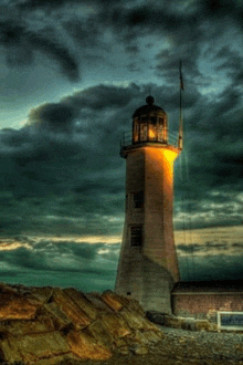 a lighthouse is lit up in the dark with a cloudy sky in the background