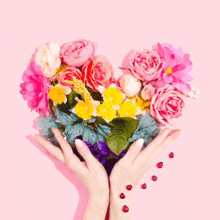 a woman is holding a heart made of flowers .