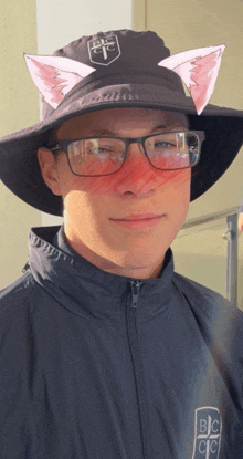 a man wearing glasses and a hat with a bc logo on it