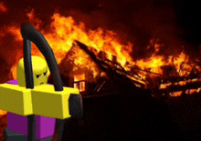 a yellow and purple lego figure stands in front of a burning house