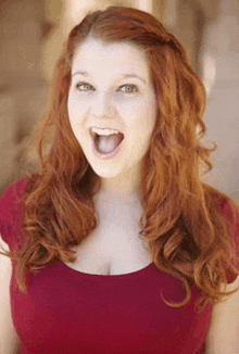 a woman with red hair and a red top is making a funny face .